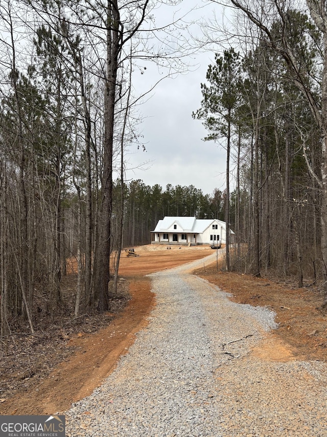 view of road with gravel driveway and a forest view