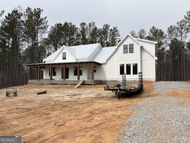 modern farmhouse featuring board and batten siding, covered porch, and metal roof