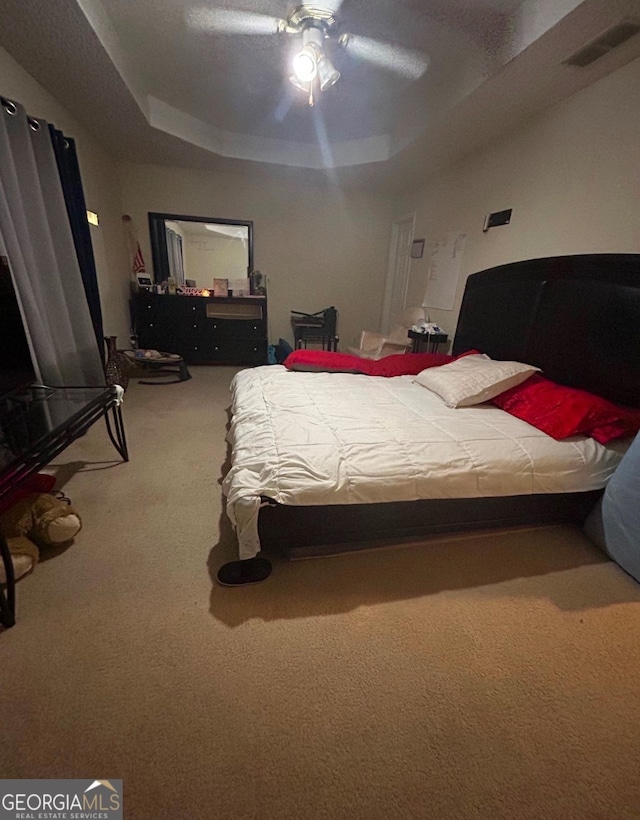 bedroom with ceiling fan, carpet, and a raised ceiling