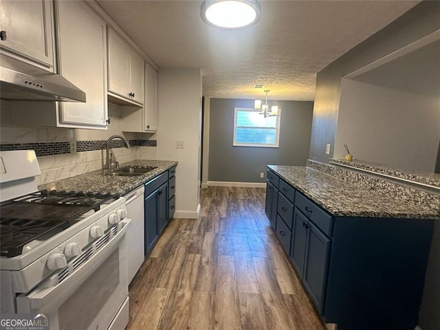 kitchen with white range with gas cooktop, sink, blue cabinetry, dark stone countertops, and white cabinetry