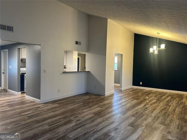 unfurnished living room with a chandelier, high vaulted ceiling, dark wood-type flooring, and a textured ceiling