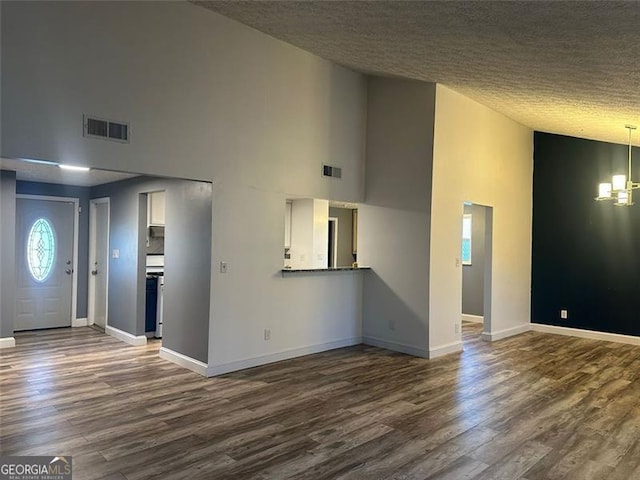 unfurnished living room with dark hardwood / wood-style flooring, a textured ceiling, and high vaulted ceiling