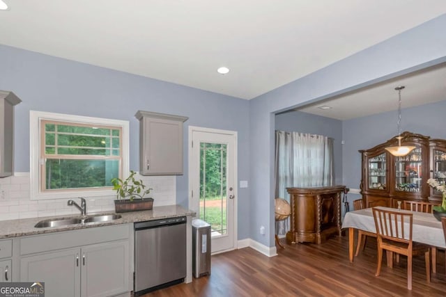 kitchen with sink, dark wood-type flooring, tasteful backsplash, stainless steel dishwasher, and pendant lighting