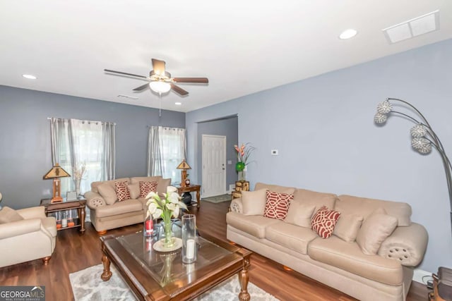 living room featuring ceiling fan and dark wood-type flooring