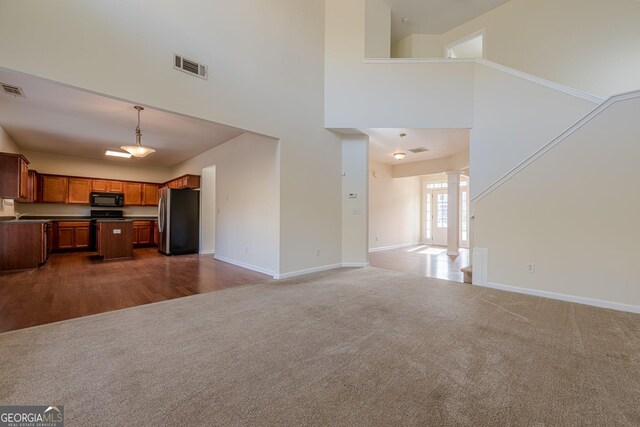 unfurnished living room with visible vents, baseboards, dark carpet, and ornate columns