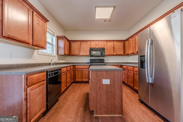 kitchen featuring dark countertops, black appliances, wood finished floors, and a center island