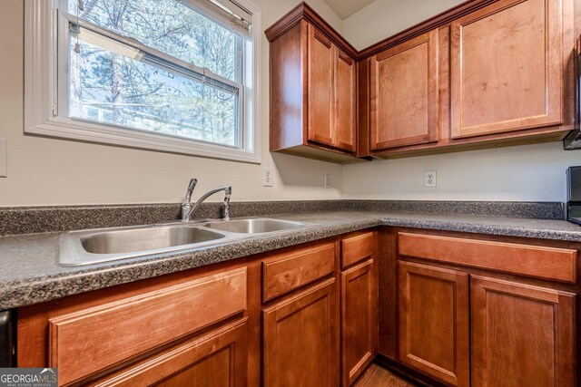 kitchen featuring a sink, brown cabinets, and dark countertops