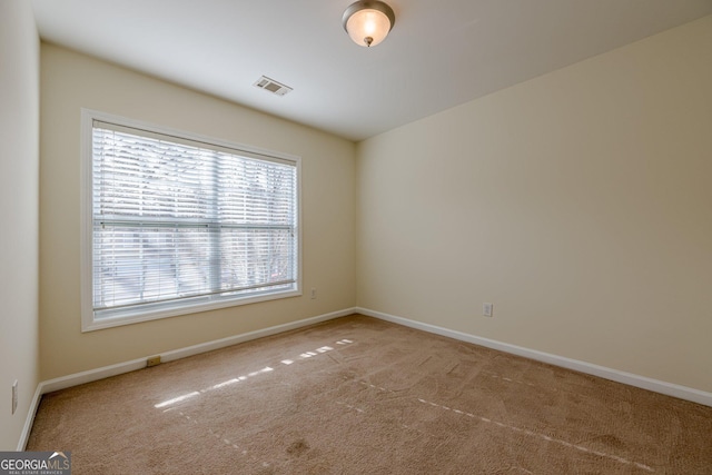 carpeted spare room featuring visible vents and baseboards