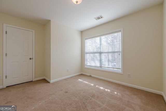 spare room featuring visible vents, carpet flooring, and baseboards