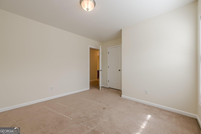 spare room featuring baseboards and light carpet