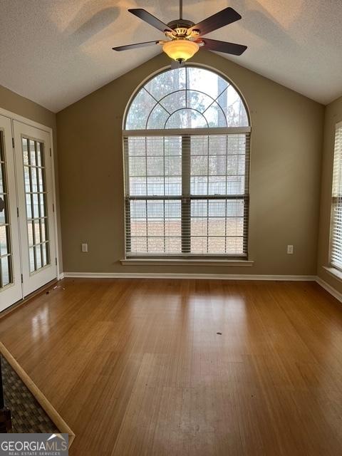 unfurnished room featuring a healthy amount of sunlight, lofted ceiling, and wood-type flooring