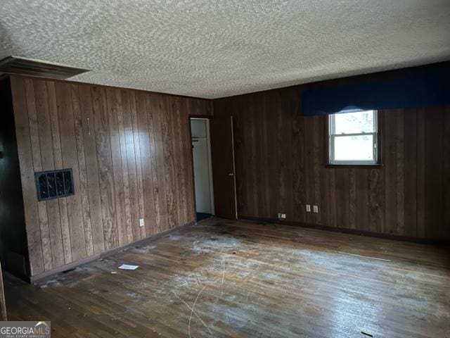 spare room featuring dark wood-type flooring and wooden walls