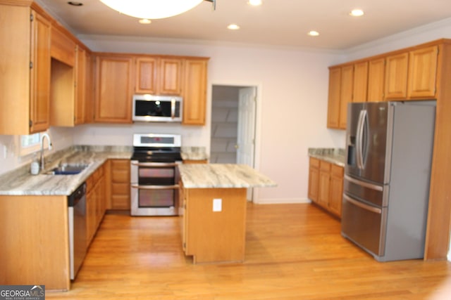 kitchen with sink, a center island, light wood-type flooring, appliances with stainless steel finishes, and ornamental molding