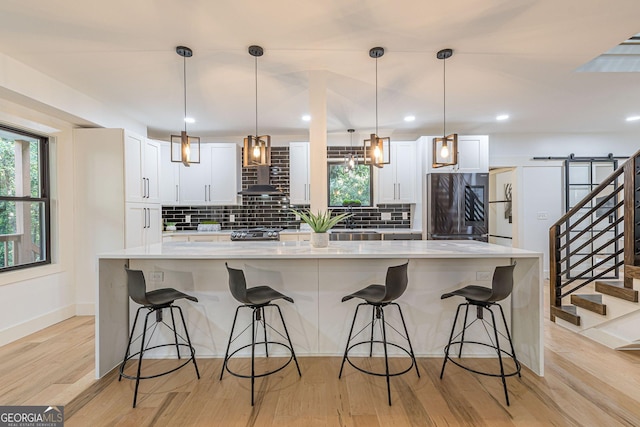 kitchen featuring ceiling fan, pendant lighting, light hardwood / wood-style flooring, white cabinets, and stainless steel microwave