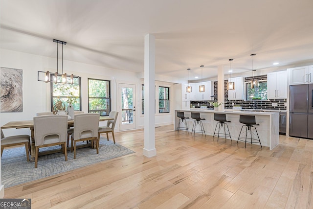 kitchen with pendant lighting, a spacious island, a barn door, white cabinetry, and stainless steel refrigerator