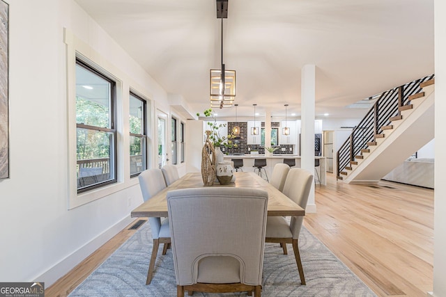 dining space with light hardwood / wood-style floors, a healthy amount of sunlight, and a notable chandelier