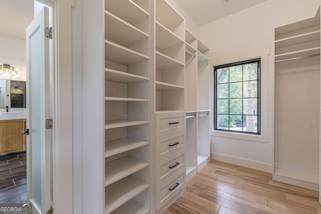 bedroom with ensuite bathroom, a barn door, wood-type flooring, and ceiling fan