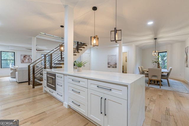 kitchen featuring white cabinets, pendant lighting, stainless steel appliances, and light stone counters