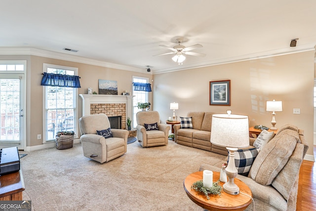 carpeted living room with a brick fireplace, ceiling fan, and crown molding