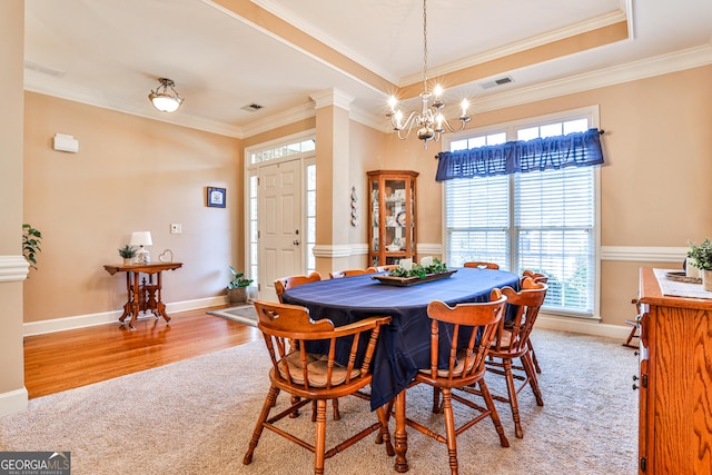 dining room featuring a tray ceiling, light colored carpet, a chandelier, and ornamental molding