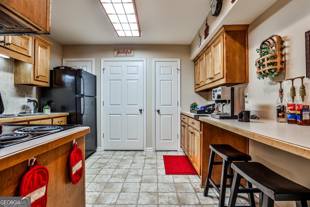 kitchen with decorative backsplash, a breakfast bar, and black fridge