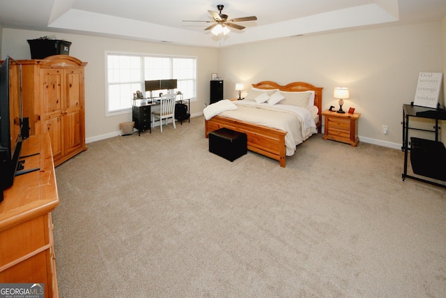 bedroom featuring a tray ceiling, ceiling fan, and light colored carpet