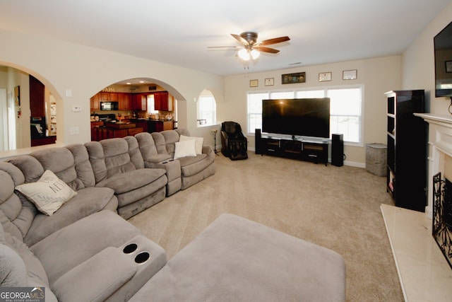 carpeted living room with ceiling fan and a fireplace