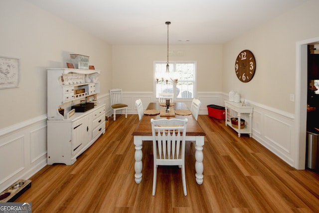 dining area with hardwood / wood-style flooring and an inviting chandelier