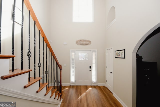 foyer entrance with wood-type flooring and a high ceiling