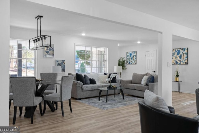 living room featuring light hardwood / wood-style floors, crown molding, and a notable chandelier