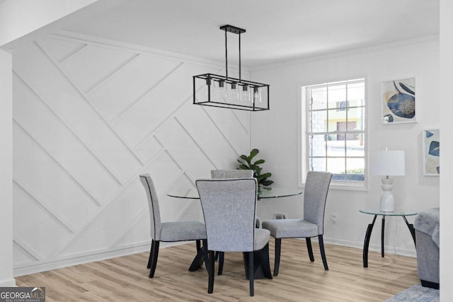 dining space with light hardwood / wood-style floors and ornamental molding