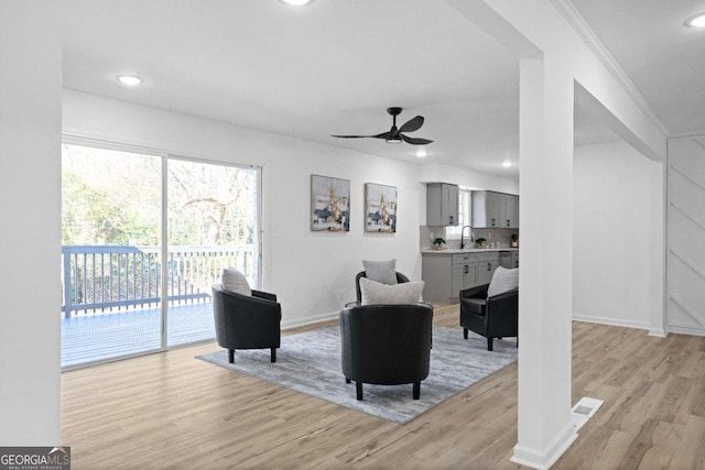 living room featuring ceiling fan, light hardwood / wood-style floors, and sink