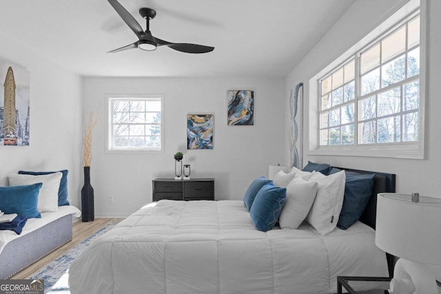 bedroom featuring ceiling fan, light hardwood / wood-style flooring, and multiple windows