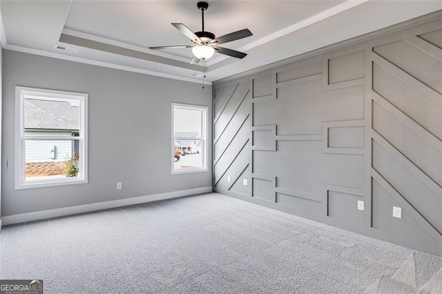 carpeted empty room with a raised ceiling, crown molding, and ceiling fan