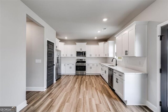 unfurnished living room with high vaulted ceiling, a stone fireplace, sink, ceiling fan, and wood-type flooring