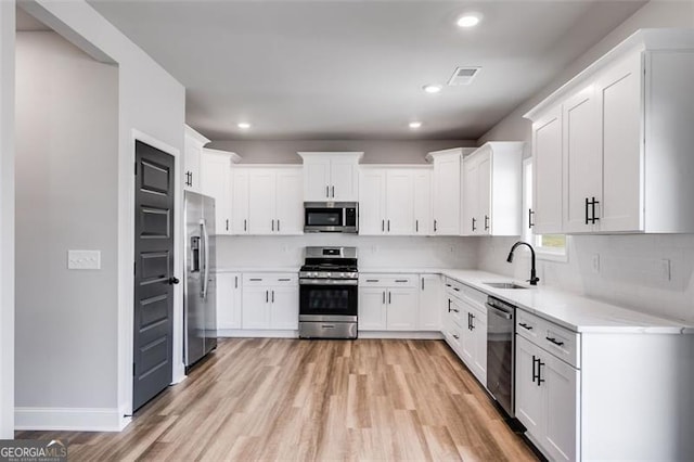 kitchen with decorative backsplash, white cabinetry, sink, and appliances with stainless steel finishes