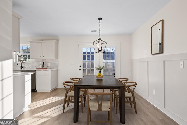 dining space with a notable chandelier, light hardwood / wood-style floors, and sink