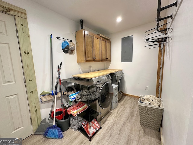 laundry room featuring cabinets, light wood-type flooring, electric panel, and washer and clothes dryer