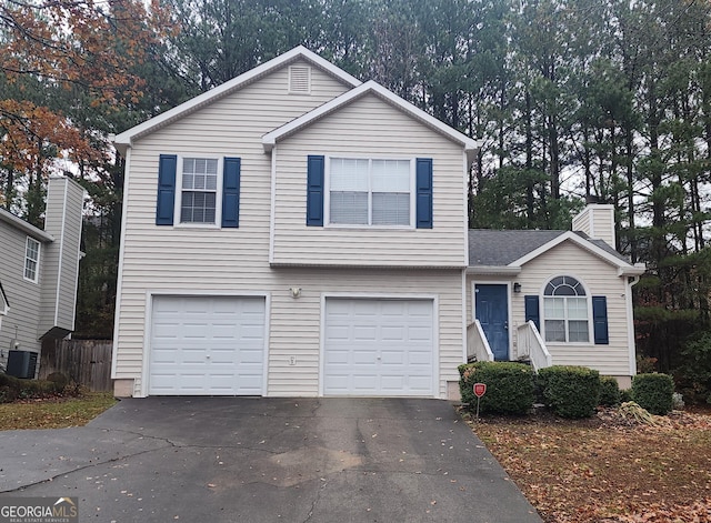 view of front of house with a chimney, fence, an attached garage, aphalt driveway, and central AC