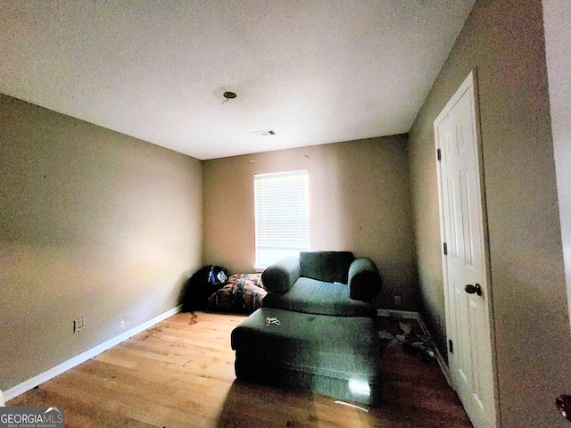 living area featuring visible vents, baseboards, and wood finished floors