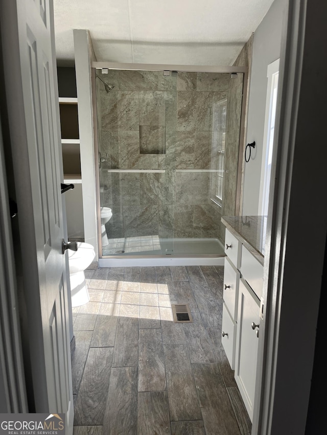 bathroom with vanity, toilet, and a shower with door