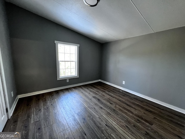 unfurnished room featuring dark hardwood / wood-style floors and lofted ceiling