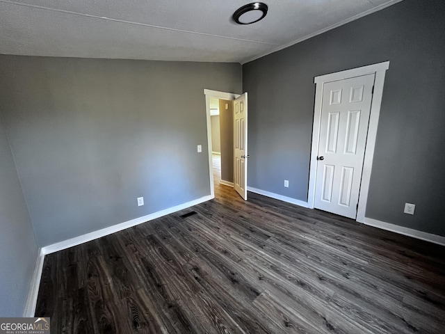 unfurnished bedroom with dark hardwood / wood-style floors and vaulted ceiling