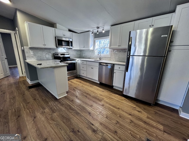 kitchen with white cabinets, dark hardwood / wood-style floors, lofted ceiling, and appliances with stainless steel finishes