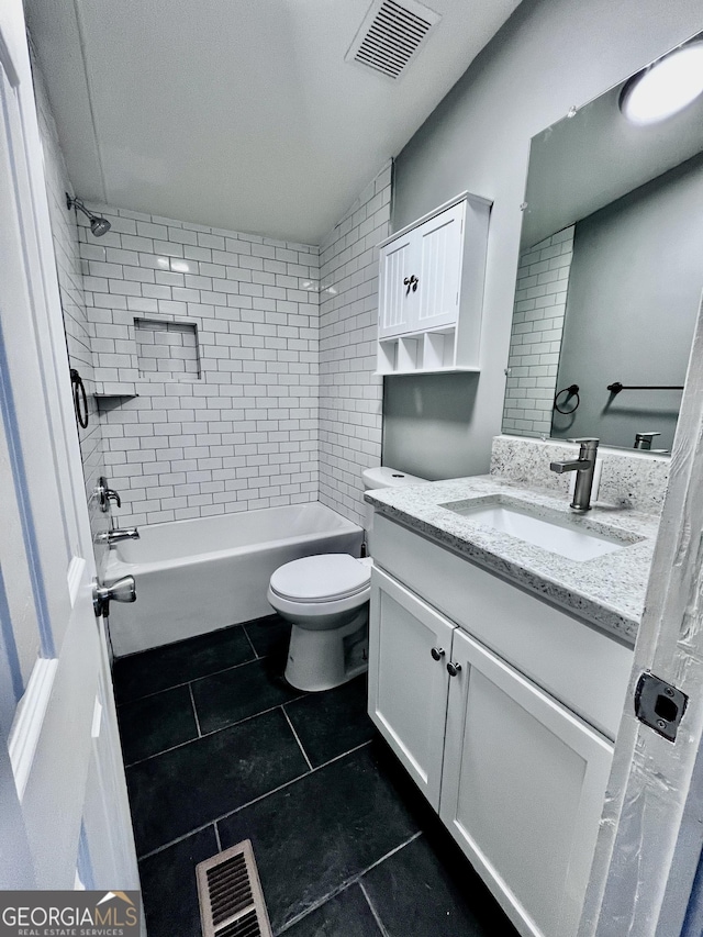 full bathroom featuring tile patterned floors, vanity, tiled shower / bath combo, and toilet