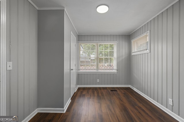 spare room featuring dark wood-type flooring and crown molding