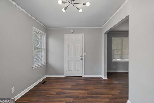 empty room with crown molding, hardwood / wood-style floors, and a chandelier