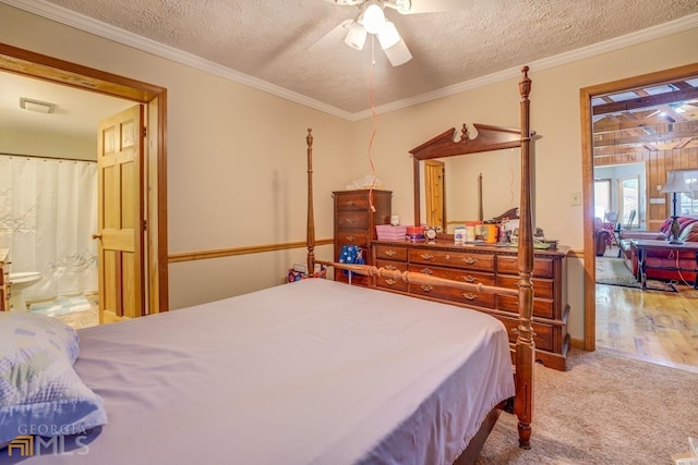 carpeted bedroom featuring crown molding, a textured ceiling, ceiling fan, and ensuite bath