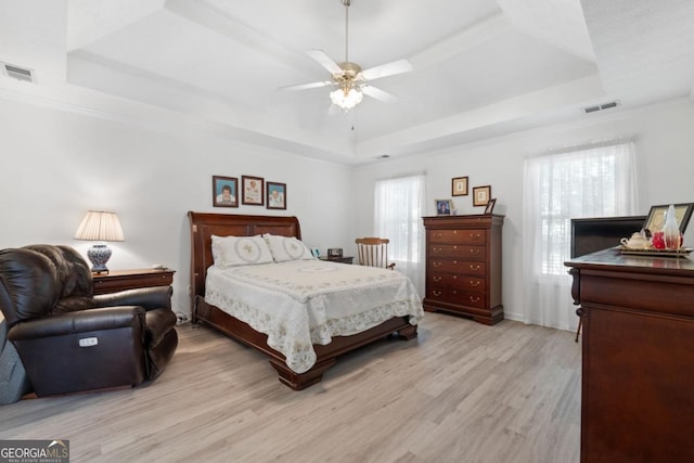 bedroom featuring ceiling fan, a raised ceiling, and multiple windows