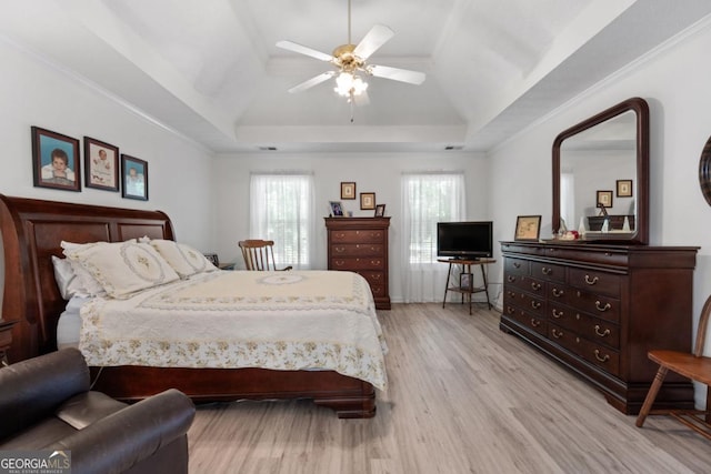 bedroom with a raised ceiling, ceiling fan, crown molding, and light wood-type flooring